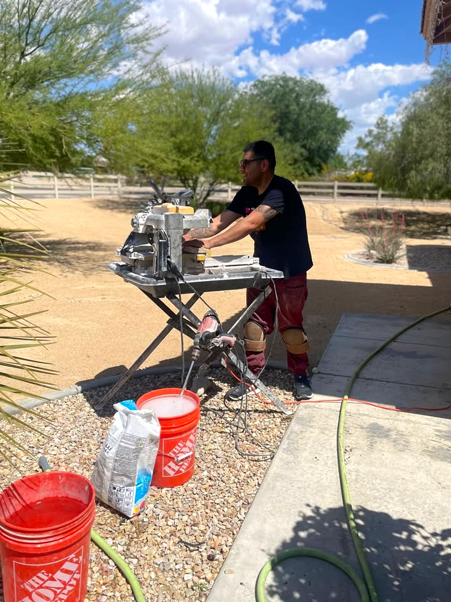 A tile setter cutting tile at a wet saw on a High Desert job site