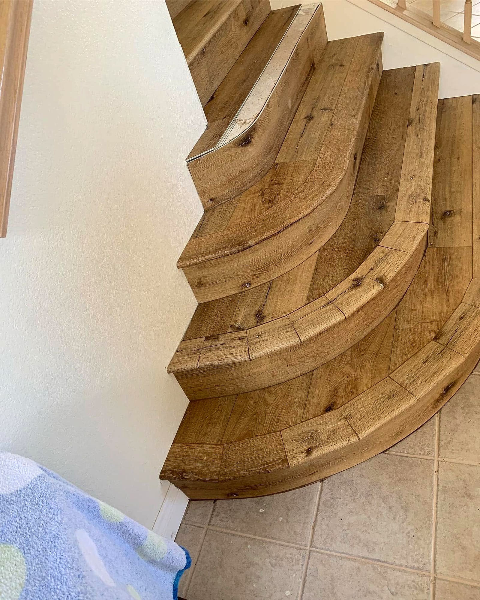 Curved bottom stairs clad in wood-look planks