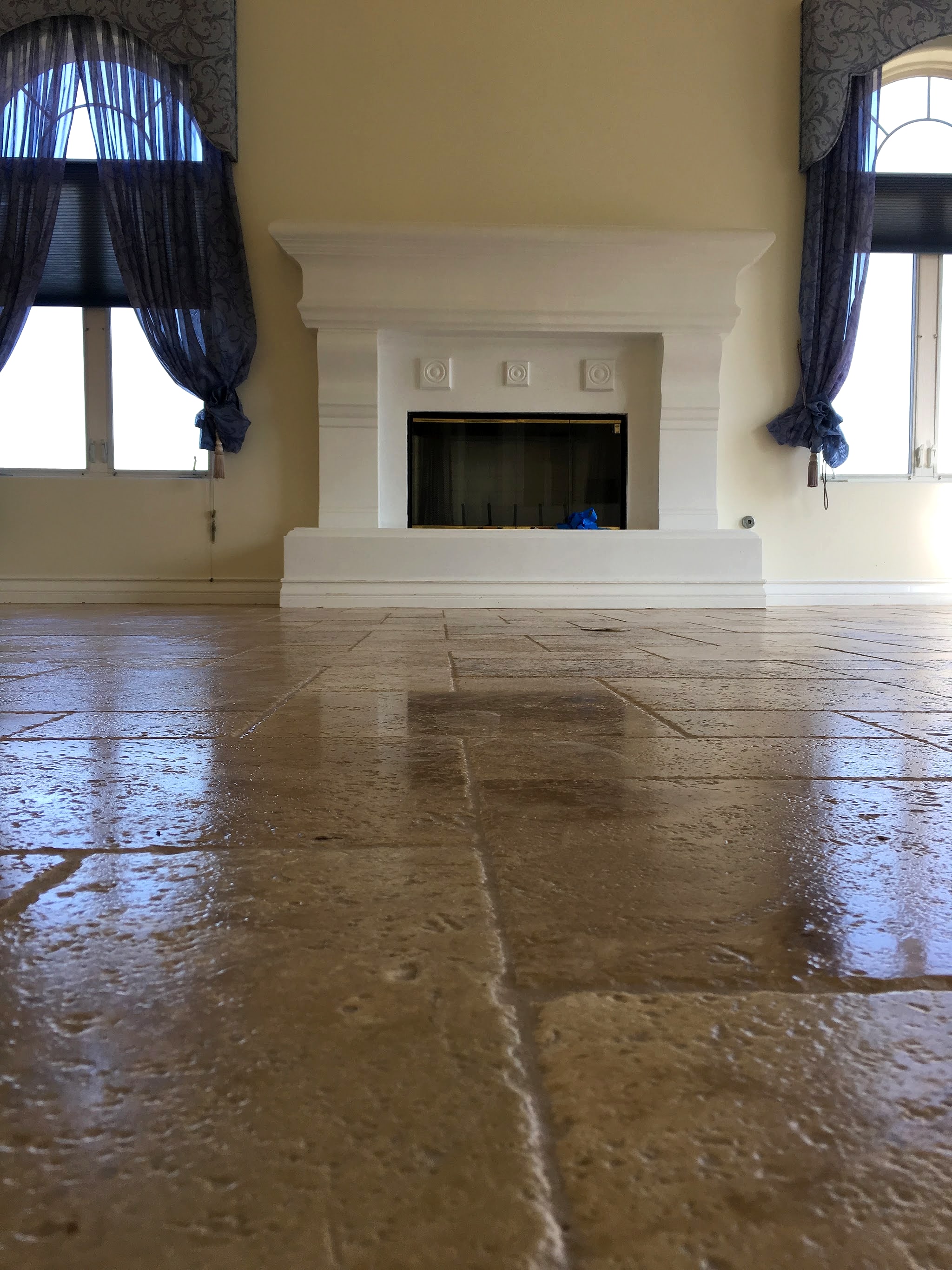 Travertine tile floor in front of a white fireplace
